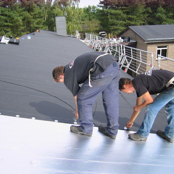 Twee mannen leggen bitumen dak aan